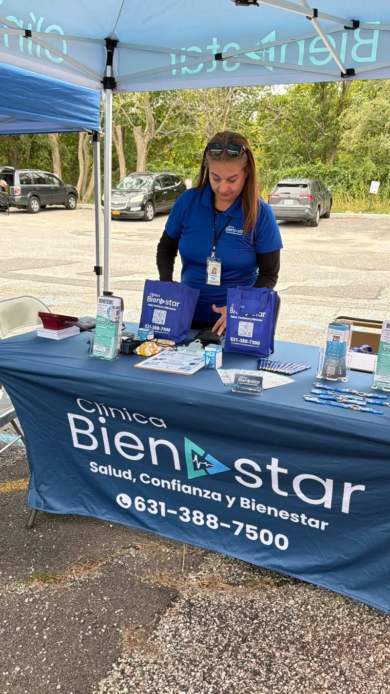 Stand de Clínica Bienestar en el Festival de Long Island, con una integrante del equipo preparando los materiales