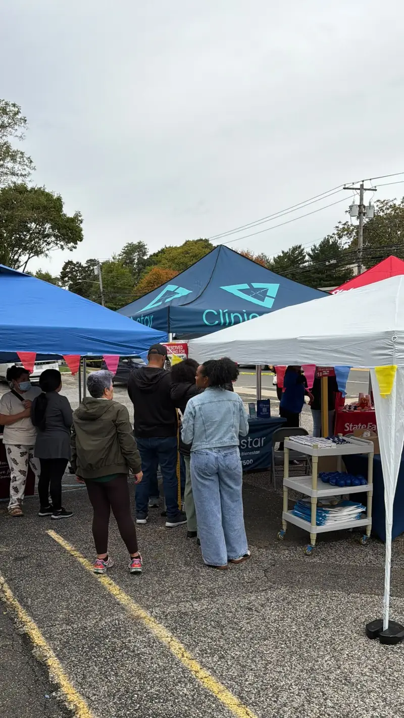 Carpa de Clínica Bienestar entre los expositores del Festival de Long Island, con visitantes acercándose