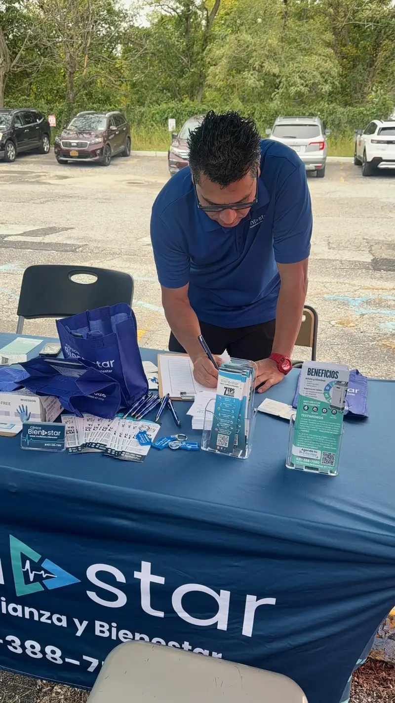 Mesa del stand de Clínica Bienestar con folletos informativos, tarjetas y bolsas para los visitantes