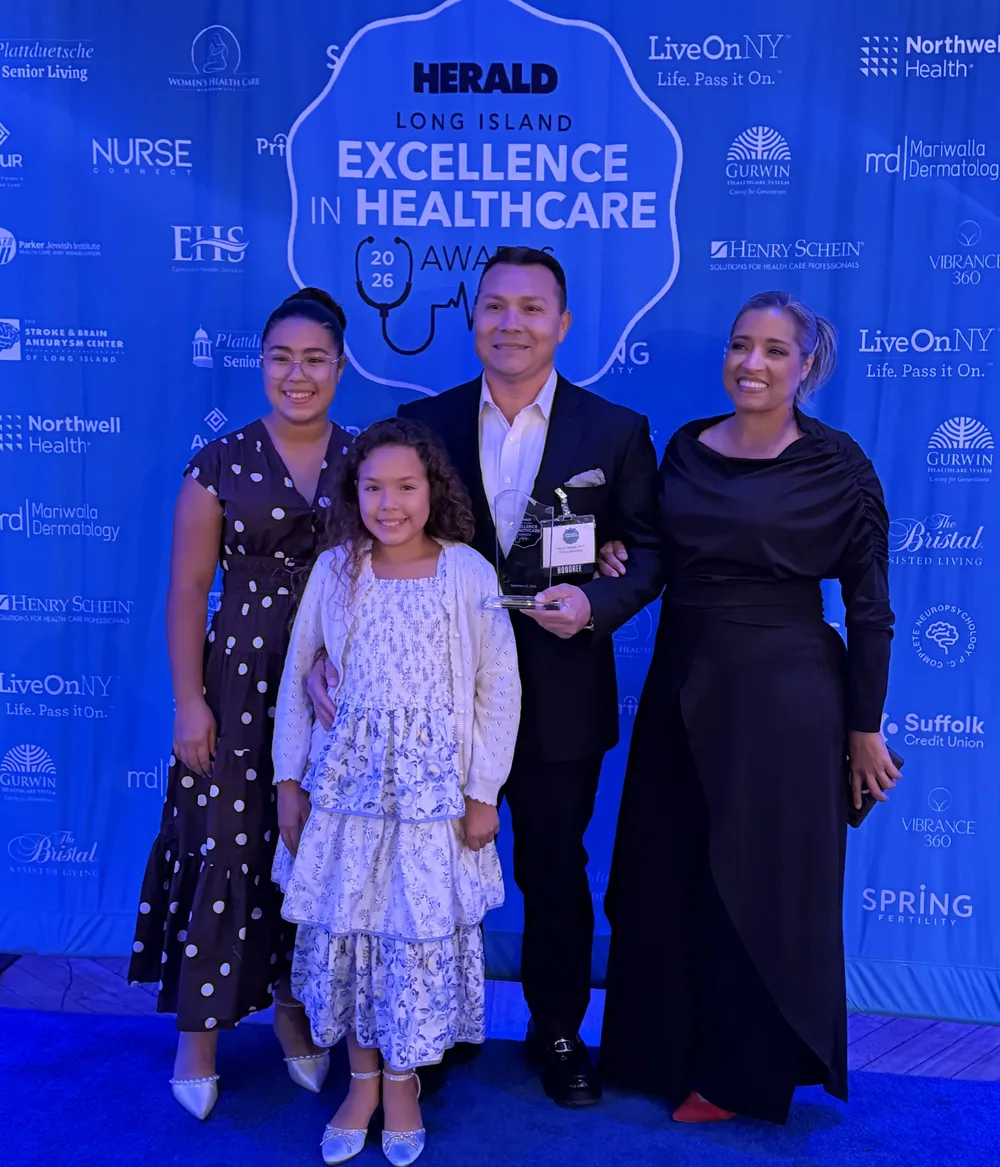 Hector Melgar, DPT, con el trofeo de los HERALD Long Island Excellence in Healthcare Awards 2026 junto a su familia